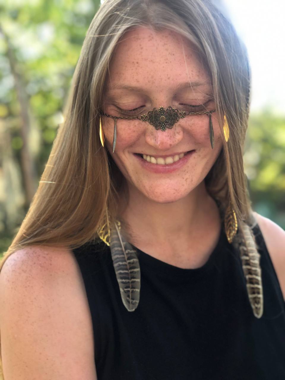 Portrait of woman wearing antique bronze facechain with feathers and floral design